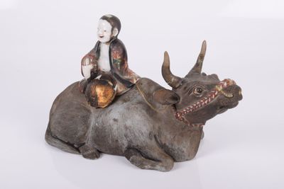 une figurine représentant un homme assis sur une vache
