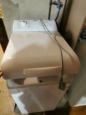 une machine à laver blanche posée sur un sèche-linge dans une pièce