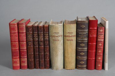 several old books are lined up in a row on a gray surface
