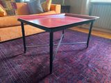 une table au plateau rouge posée sur un tapis dans un salon