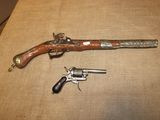 un vieux pistolet et un revolver sont posés sur une table