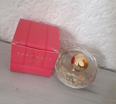 un coffret de parfum rose posé sur une table à côté d'un autre coffret de parfum rose