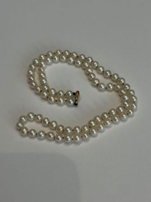 collier de perles avec un fermoir en or sur fond blanc