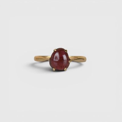 un gros plan d'une bague en pierre rouge posée sur une surface blanche