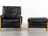 pair of black leather lounge chairs and foot stools with wooden legs
