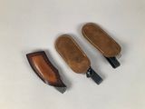 three leather sheaths and a knife on a white surface