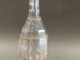 a clear glass bottle with a gold decoration on it