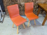 deux chaises orange placées l'une à côté de l'autre près d'une table