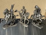 three figurines of men riding on horses on a table