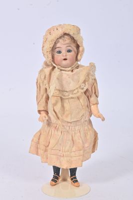 une poupée à l'ancienne, coiffée d'un bonnet et vêtue d'une robe, posée sur un fond blanc