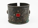 un gros plan sur un bracelet en métal orné d'une pierre rouge au centre