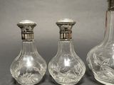 three clear glass decanters with silver tops on a table