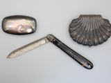 a knife, a shell, and a pocket knife on a table