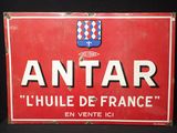 une vieille enseigne rouge et blanche sur laquelle figure un blason