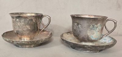 deux tasses et soucoupes en argent posées sur une table