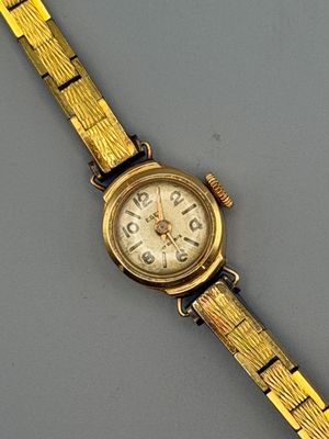 an image of a gold wrist watch with a white face on a gray surface