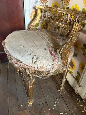 une chaise dont le siège a été arraché, dans un coin de la pièce