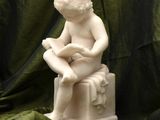a statue of a boy sitting on a box reading a book