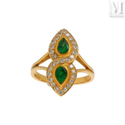 un gros plan d'une bague en or sertie de pierres vertes et de diamants