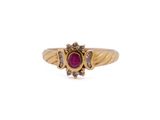 a close up of a gold ring with a ruby stone