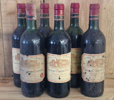 six bottles of red wine are lined up on a wooden shelf