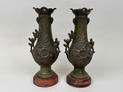 pair of antique bronze vases on marble bases on a white background