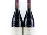 two bottles of red wine sitting next to each other on a white surface