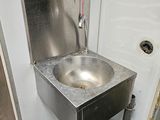 a metal sink in the corner of a public restroom