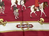a red scarf with a picture of people riding horses on it