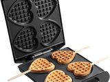 a close up of a waffle maker with four heart shaped waffles