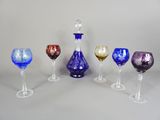 plusieurs verres à vin de différentes couleurs et une carafe posés sur une table