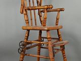 une vieille chaise haute en bois munie de roulettes et d'une assise en bois