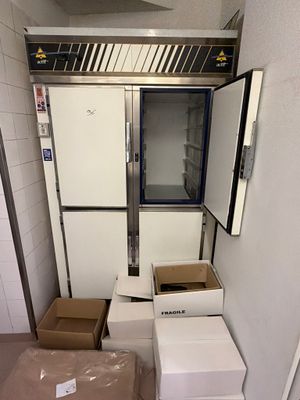 un réfrigérateur au milieu d'une pièce, avec des cartons par terre