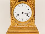 a gold clock with roman numerals on the face