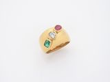 un gros plan d'une bague en or sertie d'une pierre verte et rouge
