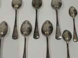 six spoons and a spoon rest in a row on a white surface