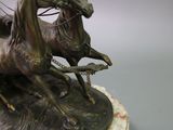 a bronze statue of two horses and a man on a horse drawn carriage
