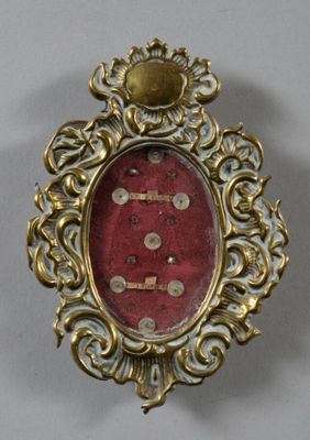 une photo d'une broche rouge et dorée posée sur une table