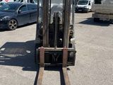 a forklift in a parking lot with a truck in the background