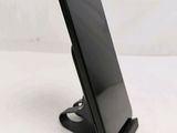 a close up of a cell phone on a stand on a white surface