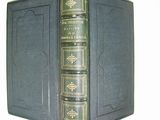 an old book with a green cover sitting on top of a book case