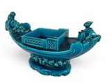 blue ceramic figurine of a boat with people on it