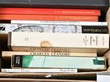 many books in a box that are stacked on top of each other