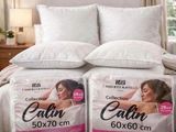 two pillows on top of a bed in a bedroom next to a window