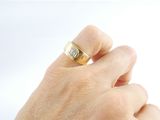 a person ' s hand holding a gold ring with a diamond on it