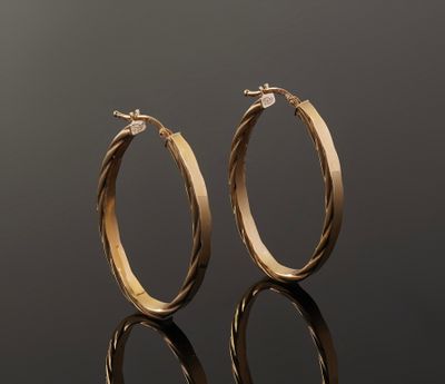 a pair of gold hoop earrings on a reflective surface
