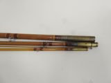 three wooden and brass fishing rods on a white surface