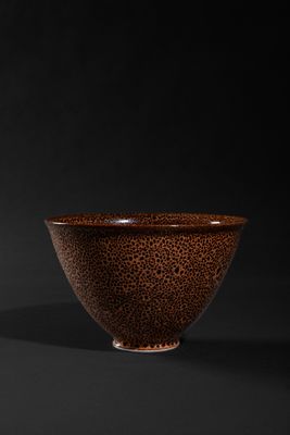 a brown and black bowl sitting on top of a black surface