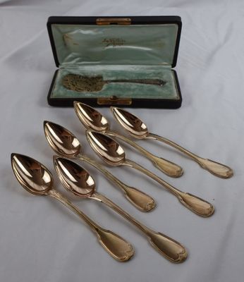six silver spoons in a case on a white table cloth
