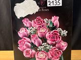 des roses roses dans une boîte posée sur une table, sur fond noir